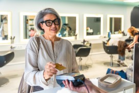 Une femme approche sa carte de paiement d’un terminal de paiement sans contact.